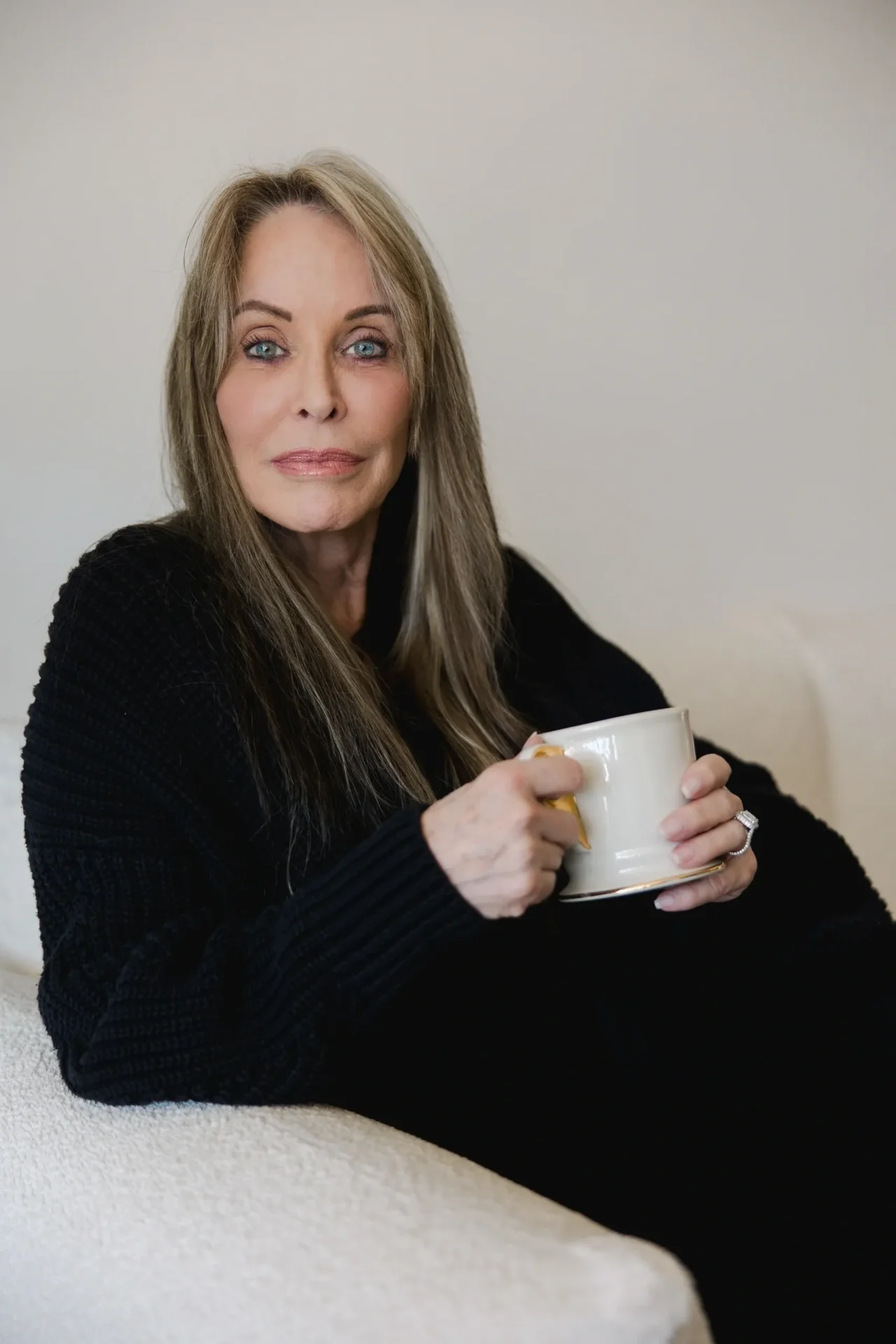 A woman sitting on the couch holding a mug.